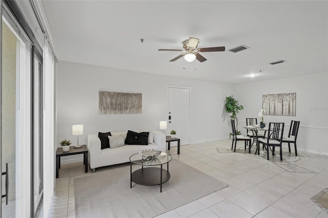 living room featuring ceiling fan, light tile patterned floors, and baseboards