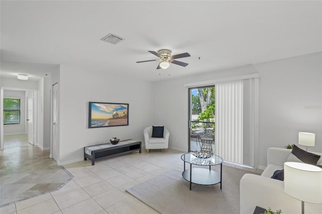 living area with baseboards, a ceiling fan, and light tile patterned floors
