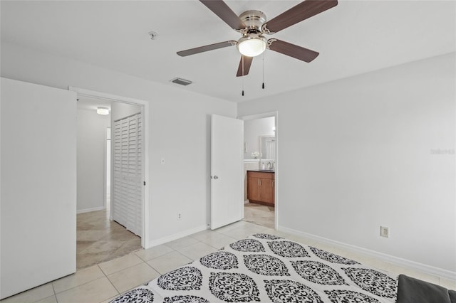 bedroom with light tile patterned floors, baseboards, and connected bathroom