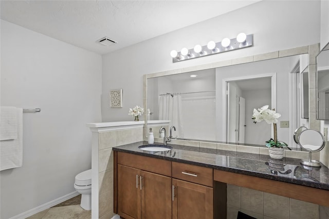 bathroom featuring toilet, curtained shower, vanity, tile patterned flooring, and baseboards