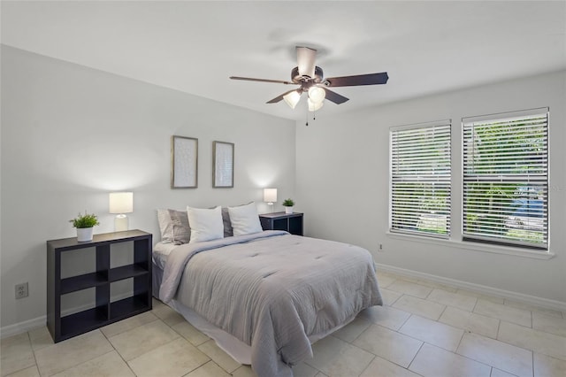 bedroom featuring baseboards, light tile patterned floors, and a ceiling fan