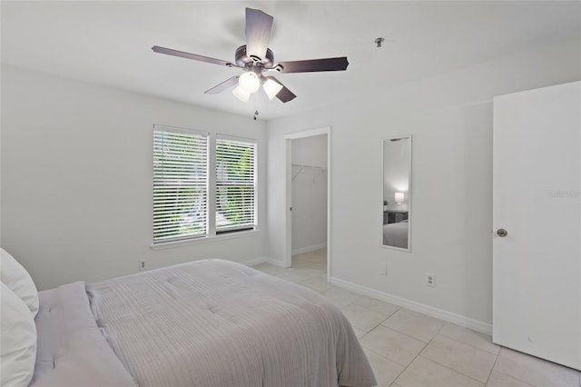 bedroom with light tile patterned floors, a spacious closet, baseboards, and ceiling fan