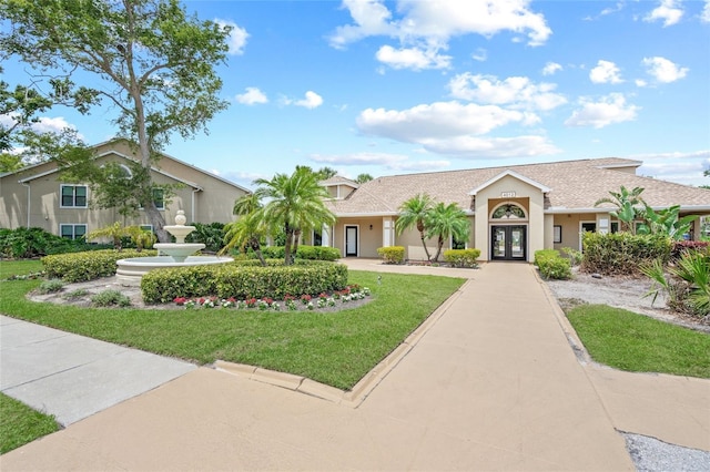view of front facade featuring french doors, a front yard, and stucco siding
