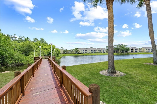 dock area with a residential view, a lawn, and a water view