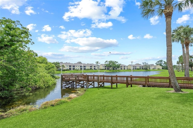 dock area with a residential view, a water view, and a lawn