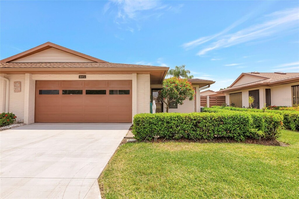 4471 Atwood Cay Cir Unit 13, Sarasota, FL 34233 - view of front of property featuring concrete driveway, a garage, and a front lawn