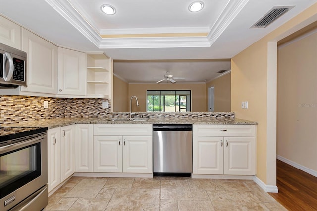 4471 Atwood Cay Cir Unit 13, Sarasota, FL 34233 - kitchen featuring stainless steel appliances, a sink, crown molding, a raised ceiling, and tasteful backsplash