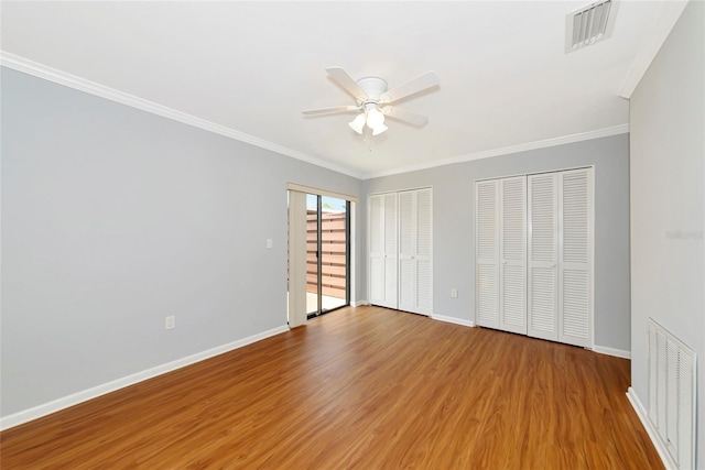 4471 Atwood Cay Cir Unit 13, Sarasota, FL 34233 - unfurnished bedroom featuring wood finished floors, baseboards, ornamental molding, two closets, and ceiling fan