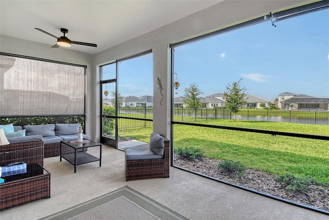 sunroom / solarium featuring a ceiling fan, an outdoor living space, a water view, and a residential view