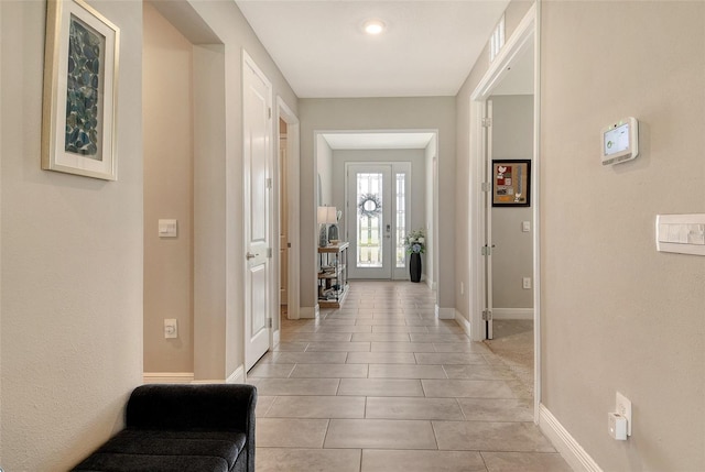 hallway with baseboards and light tile patterned flooring