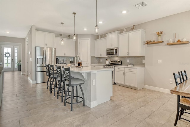 kitchen with stainless steel appliances, a kitchen bar, tasteful backsplash, light countertops, and recessed lighting