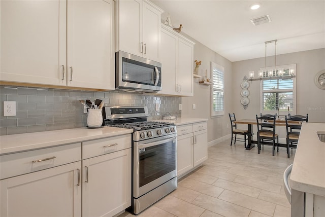 kitchen with stainless steel appliances, light countertops, backsplash, and a chandelier