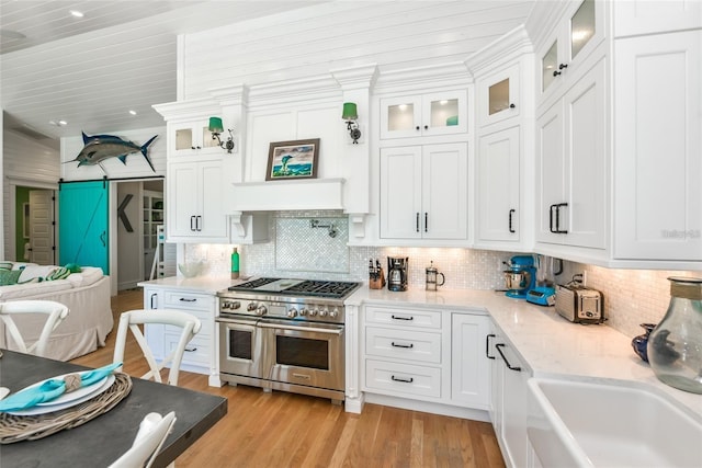 102 48th St, Holmes Beach, FL 34217 - kitchen featuring range with two ovens, a sink, white cabinets, light wood-style flooring, and wood ceiling
