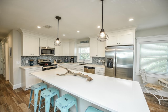 102 48th St, Holmes Beach, FL 34217 - kitchen featuring appliances with stainless steel finishes, a sink, dark wood-type flooring, backsplash, and white cabinets