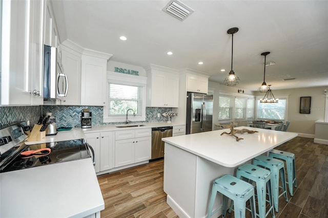 102 48th St, Holmes Beach, FL 34217 - kitchen with stainless steel appliances, a sink, wood finished floors, tasteful backsplash, and recessed lighting