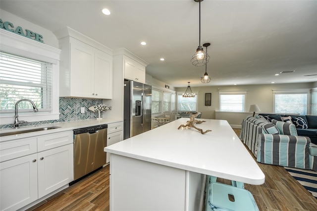 102 48th St, Holmes Beach, FL 34217 - kitchen with appliances with stainless steel finishes, a sink, open floor plan, white cabinetry, and a kitchen island
