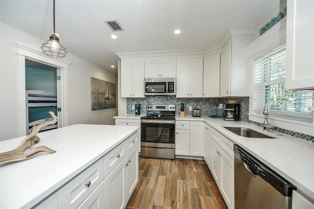 102 48th St, Holmes Beach, FL 34217 - kitchen with stainless steel appliances, a sink, backsplash, hanging light fixtures, and light countertops