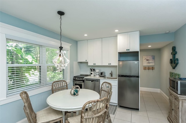 102 48th St, Holmes Beach, FL 34217 - kitchen featuring appliances with stainless steel finishes, white cabinets, baseboards, a sink, and pendant lighting