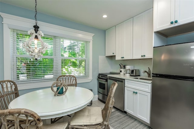 102 48th St, Holmes Beach, FL 34217 - kitchen featuring stainless steel appliances, white cabinets, backsplash, a sink, and hanging light fixtures