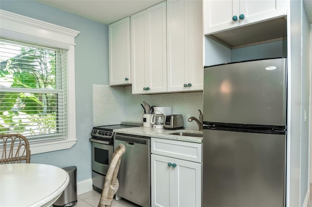 102 48th St, Holmes Beach, FL 34217 - kitchen with appliances with stainless steel finishes, a sink, white cabinetry, decorative backsplash, and light stone counters