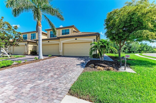 6907 Grand Estuary Trl Unit 104, Bradenton, FL 34212 - view of front of house with a tile roof, decorative driveway, a front yard, and stucco siding
