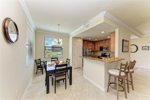 6907 Grand Estuary Trl Unit 104, Bradenton, FL 34212 - kitchen with stainless steel appliances, stone countertops, baseboards, a peninsula, and crown molding