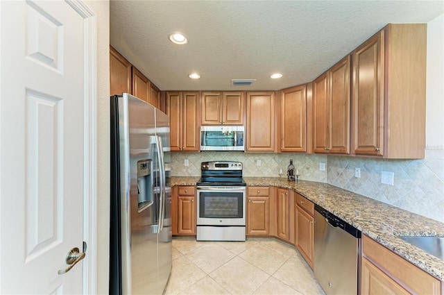 6907 Grand Estuary Trl Unit 104, Bradenton, FL 34212 - kitchen featuring appliances with stainless steel finishes, light tile patterned floors, tasteful backsplash, recessed lighting, and light stone counters