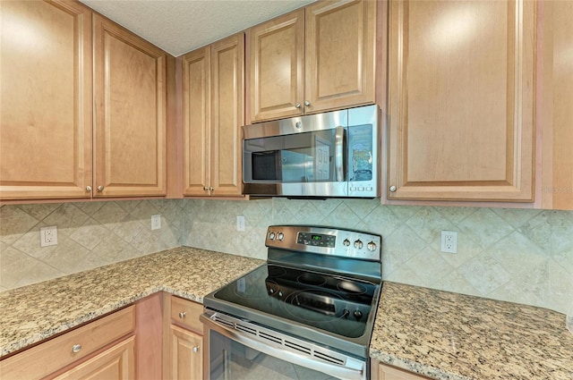 6907 Grand Estuary Trl Unit 104, Bradenton, FL 34212 - kitchen with appliances with stainless steel finishes, light stone counters, and backsplash