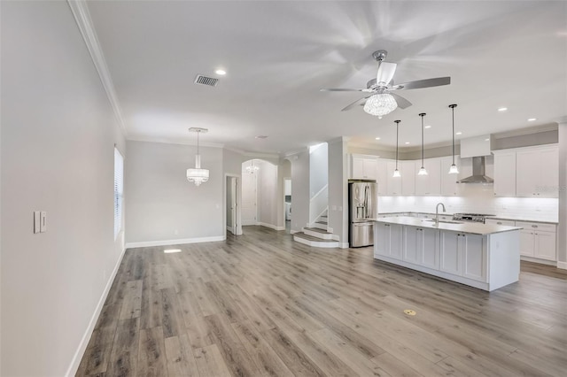 kitchen with stainless steel refrigerator with ice dispenser, ornamental molding, a sink, arched walkways, and a ceiling fan