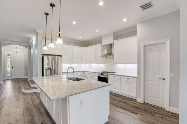 kitchen featuring a sink, wall chimney range hood, stainless steel appliances, a chandelier, and ornamental molding