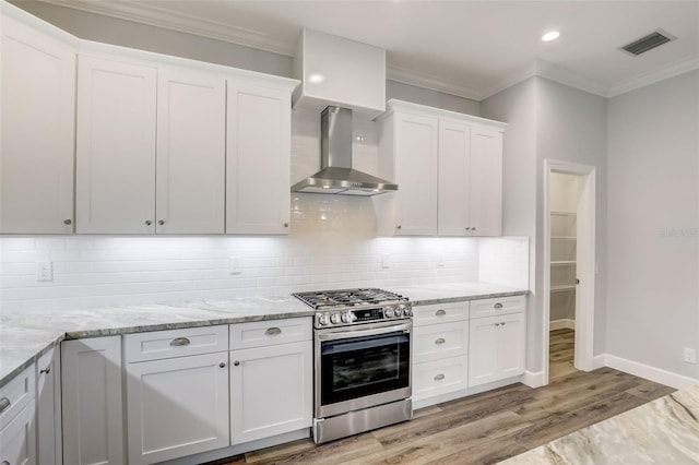 kitchen with gas stove, wall chimney range hood, light wood-style flooring, white cabinets, and crown molding