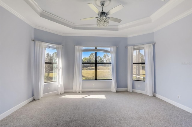 unfurnished room featuring a tray ceiling, carpet flooring, ornamental molding, ceiling fan, and baseboards