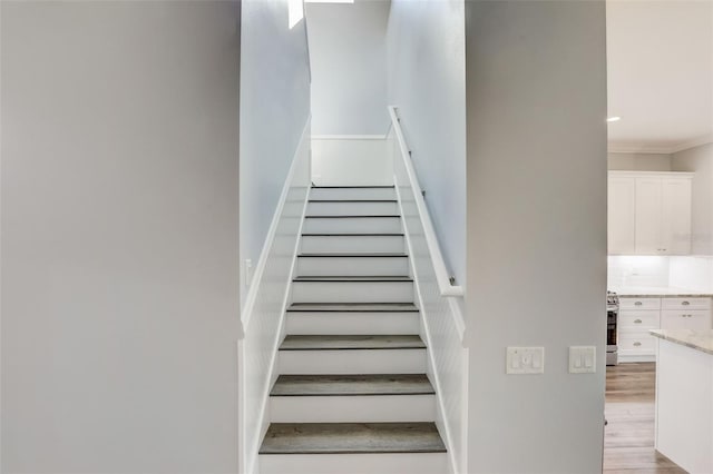 stairway featuring wood finished floors and crown molding