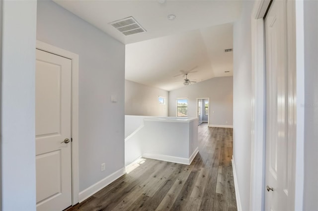 corridor with an upstairs landing, wood finished floors, lofted ceiling, and baseboards