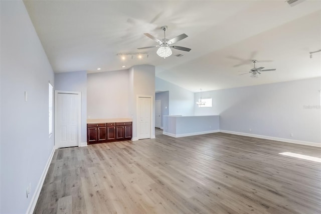 unfurnished living room featuring ceiling fan, light wood-style flooring, baseboards, and vaulted ceiling