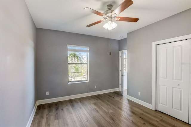 unfurnished bedroom with wood finished floors, baseboards, and ceiling fan
