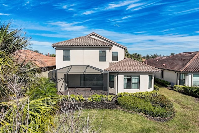 back of property featuring a tiled roof, stucco siding, and a lawn