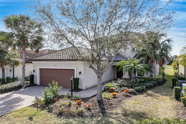 view of front of home featuring an attached garage, stucco siding, a tiled roof, and decorative driveway
