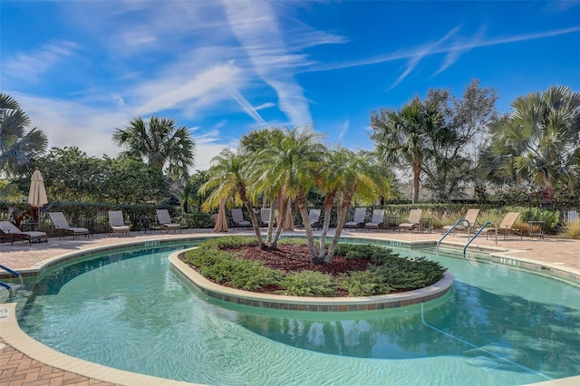 community pool with a patio area and fence