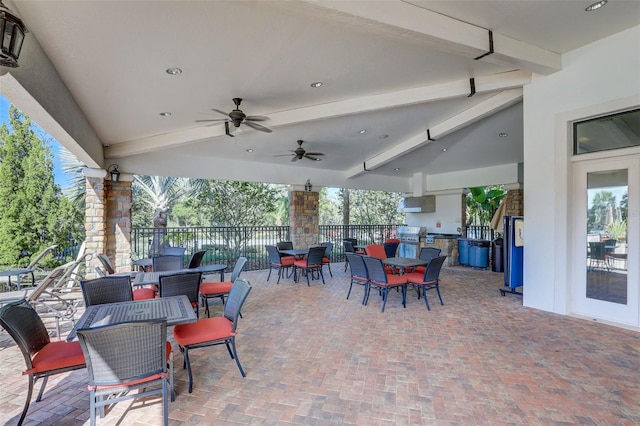 view of patio / terrace featuring outdoor dining space, exterior kitchen, fence, and ceiling fan