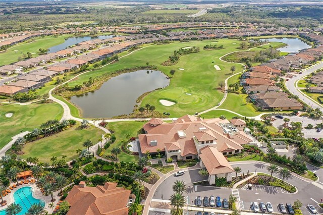 aerial view of property and surrounding area featuring a large body of water, nearby suburban area, and a local golf course