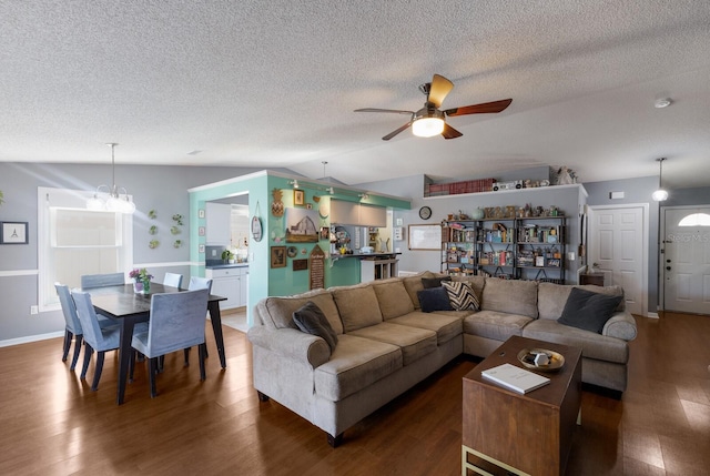 living room featuring lofted ceiling, ceiling fan, wood finished floors, a textured ceiling, and a chandelier