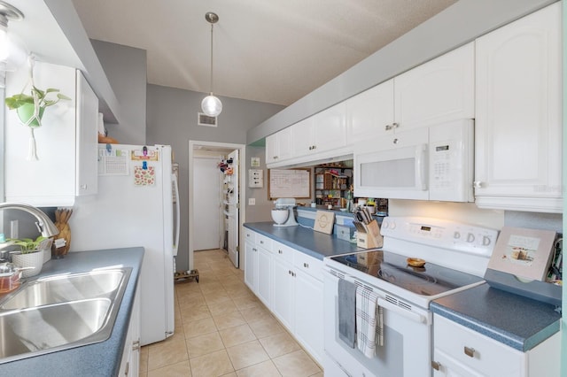 kitchen with white appliances, a sink, white cabinetry, dark countertops, and light tile patterned flooring