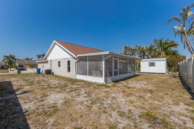 back of property featuring a sunroom, central AC, an outdoor structure, a storage shed, and fence