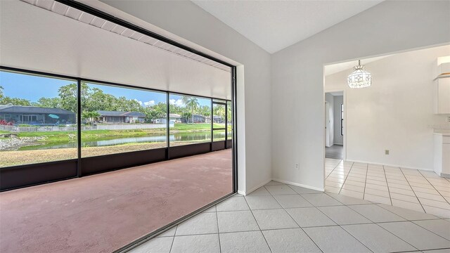 5004 32nd St E, Bradenton, FL 34203 - unfurnished room with light tile patterned floors, a chandelier, vaulted ceiling, a water view, and baseboards
