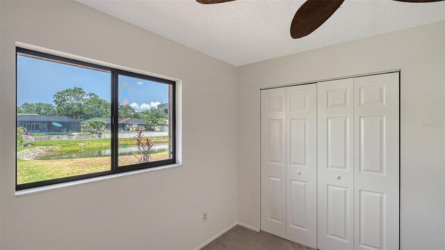 5004 32nd St E, Bradenton, FL 34203 - unfurnished bedroom with carpet flooring, a closet, a textured ceiling, ceiling fan, and baseboards