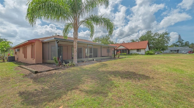 5004 32nd St E, Bradenton, FL 34203 - rear view of house with a sunroom, central air condition unit, stucco siding, and a yard