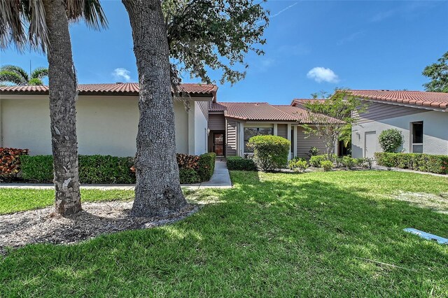 6096 Wilshire Blvd Unit 9, Sarasota, FL 34238 - view of front of home with a tile roof, a front lawn, and stucco siding