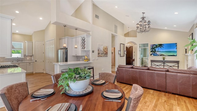 1934 Bougainvillea St, Sarasota, FL 34239 - dining space with light wood-type flooring, a chandelier, high vaulted ceiling, arched walkways, and recessed lighting
