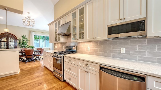 1934 Bougainvillea St, Sarasota, FL 34239 - kitchen with stainless steel appliances, under cabinet range hood, a chandelier, decorative light fixtures, and decorative backsplash